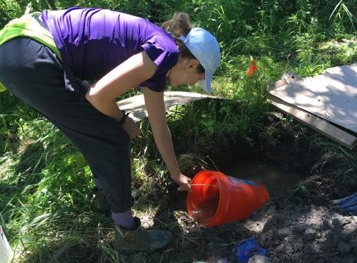 Undergraduate intern Colleen Yancey bails out a soil pit to install lysimeters and sensors.