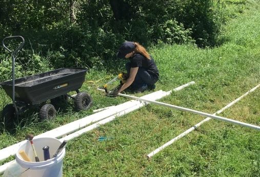 Undergraduate intern Sara Mecca saws a PVC pipe for the sensor installation.